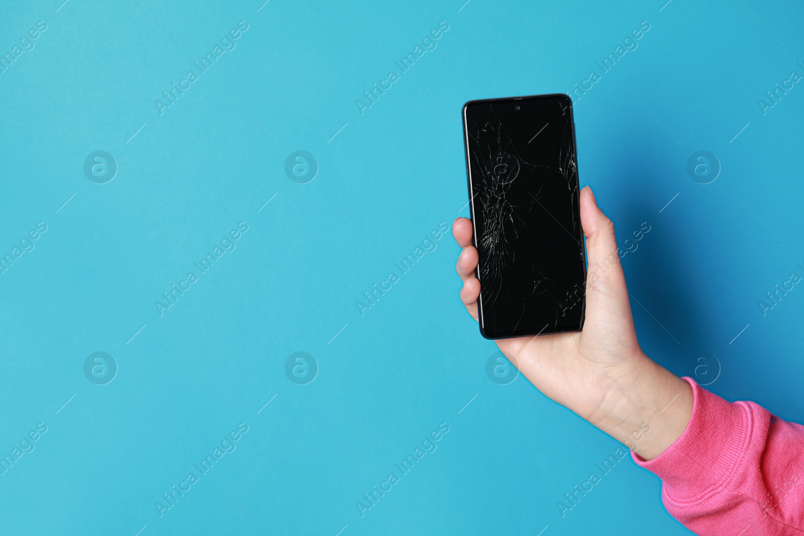 Photo of Woman holding damaged smartphone on light blue background, closeup with space for text. Device repairing