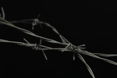 Photo of Metal barbed wire on black background, closeup