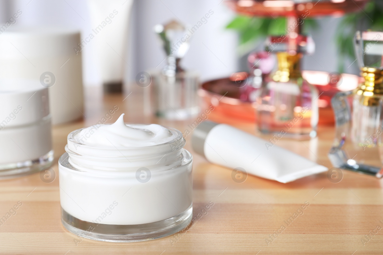 Photo of Open jar of cream on wooden dressing table. Space for text