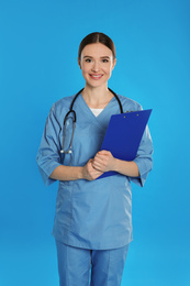 Photo of Doctor with stethoscope and clipboard on blue background