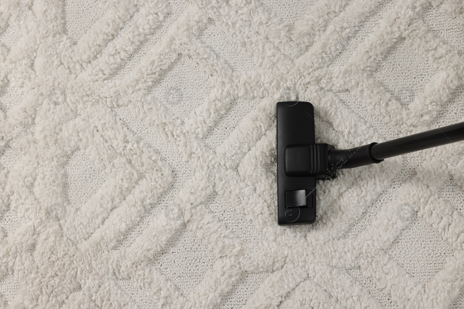 Photo of Hoovering carpet with vacuum cleaner, top view. Space for text