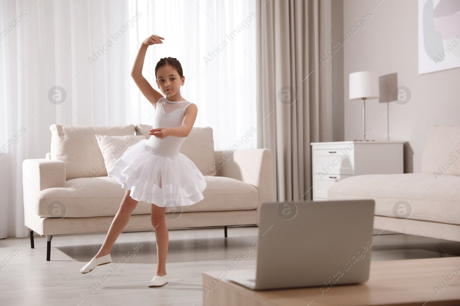 Photo of Cute little girl taking online dance class at home