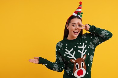 Photo of Happy young woman in Christmas sweater on orange background. Space for text