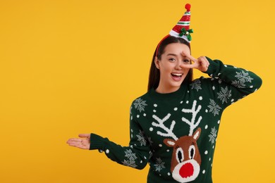 Happy young woman in Christmas sweater on orange background. Space for text