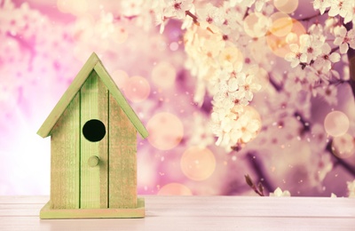 Beautiful bird house on wooden table outdoors, space for text