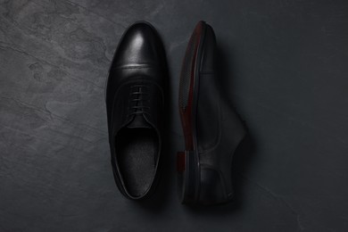 Pair of leather men shoes on black surface, top view