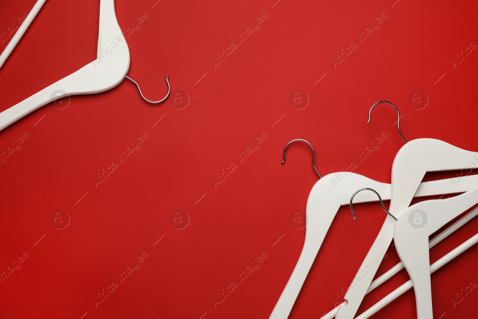 Photo of Empty clothes hangers on red background, flat lay. Space for text