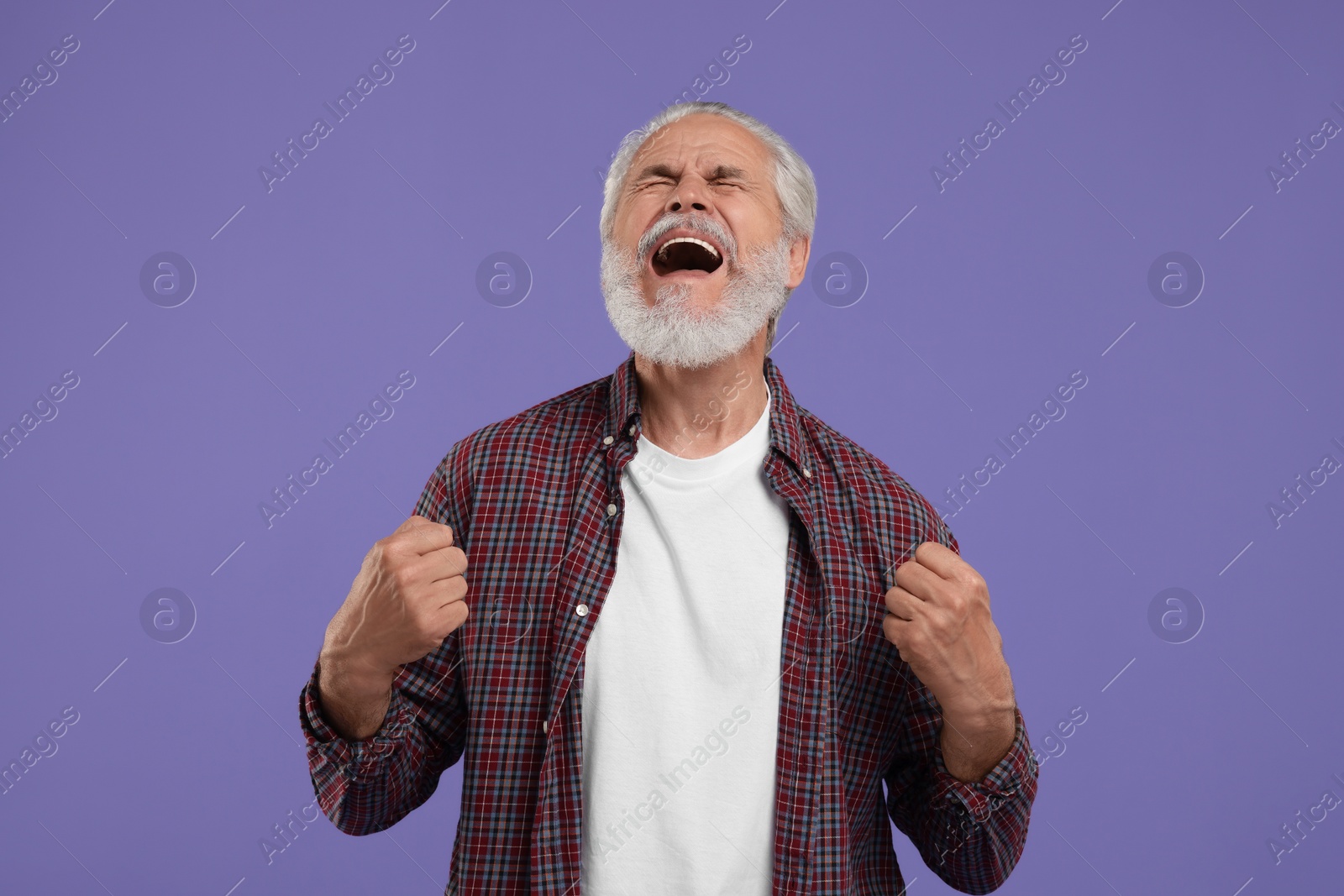 Photo of Emotional senior sports fan celebrating on purple background