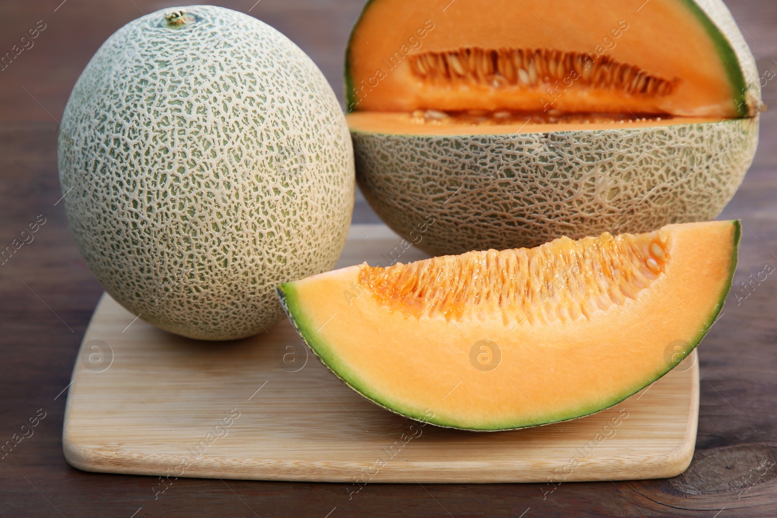 Photo of Whole and cut delicious ripe melons on wooden table, closeup