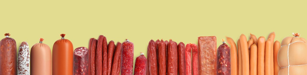 Image of Many different tasty sausages on olive color background, flat lay. Banner design