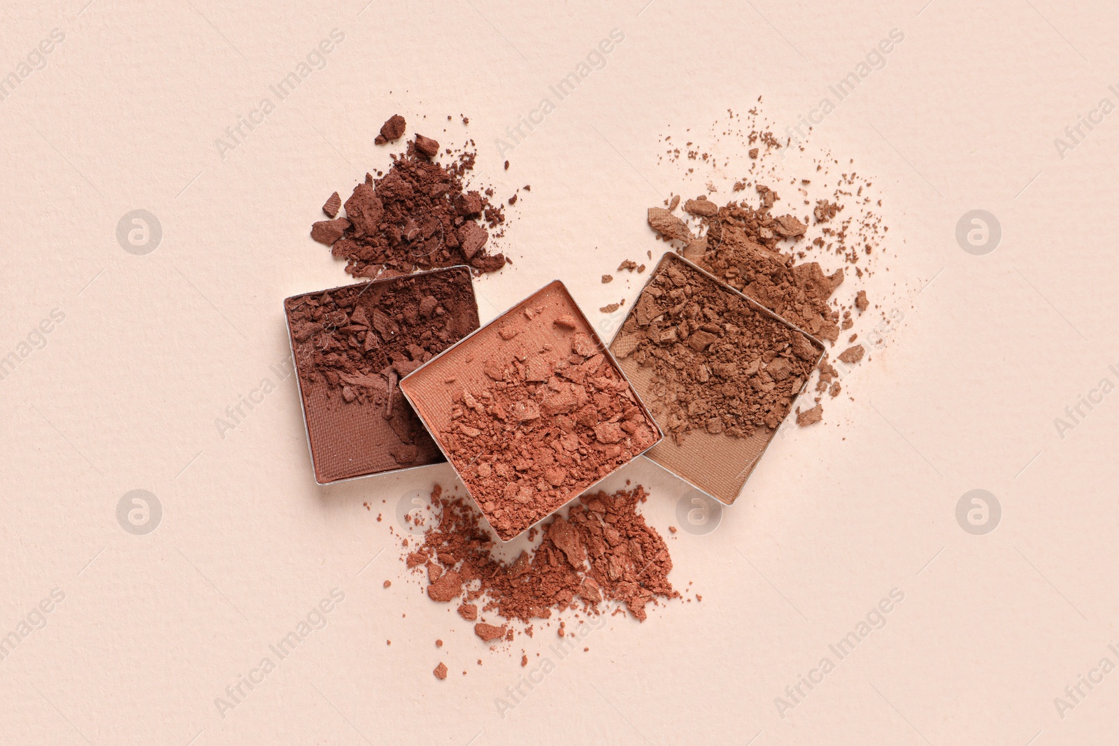 Photo of Different crushed eye shadows on beige background, flat lay