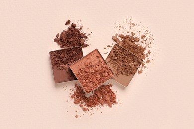 Different crushed eye shadows on beige background, flat lay