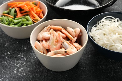 Photo of Shrimps, vegetables and noodles for cooking wok on grey textured table, closeup