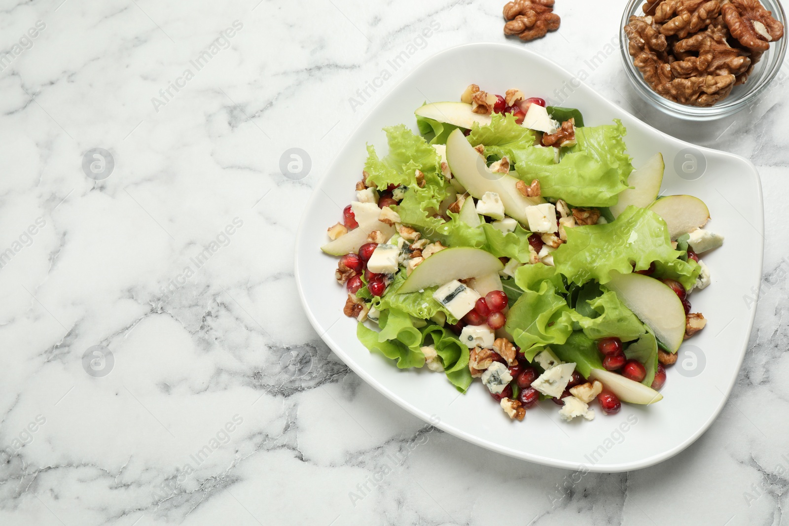 Photo of Tasty salad with pear slices and walnuts on white marble table, flat lay. Space for text