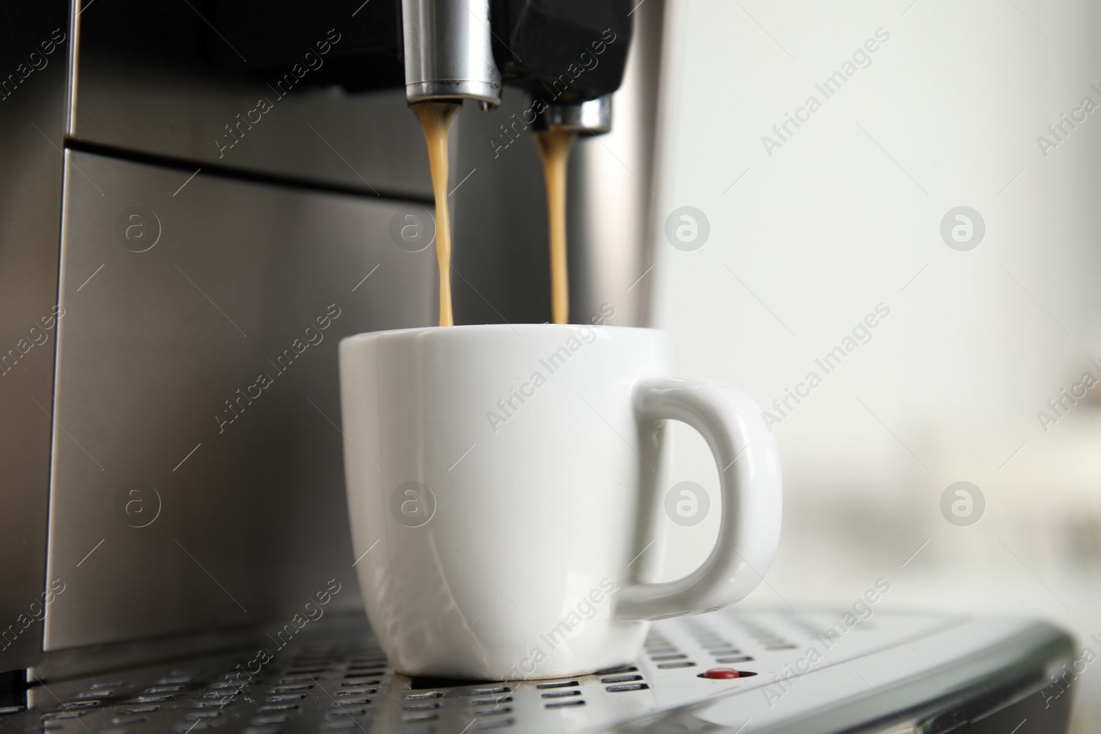 Photo of Espresso machine pouring coffee into cup against light background, closeup