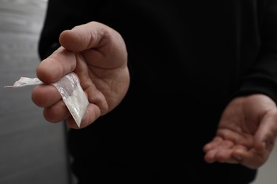 Photo of Drug addiction. Man with plastic bag of cocaine on grey background, closeup