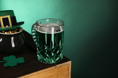 Photo of St. Patrick's day celebration. Green beer, leprechaun hat, pot of gold and decorative clover leaf on wooden table. Space for text