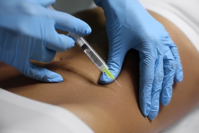 Photo of Young woman getting belly injection in salon, closeup