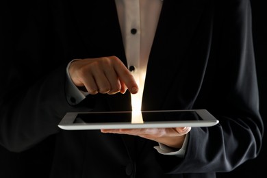 Closeup view of man using modern tablet on black background