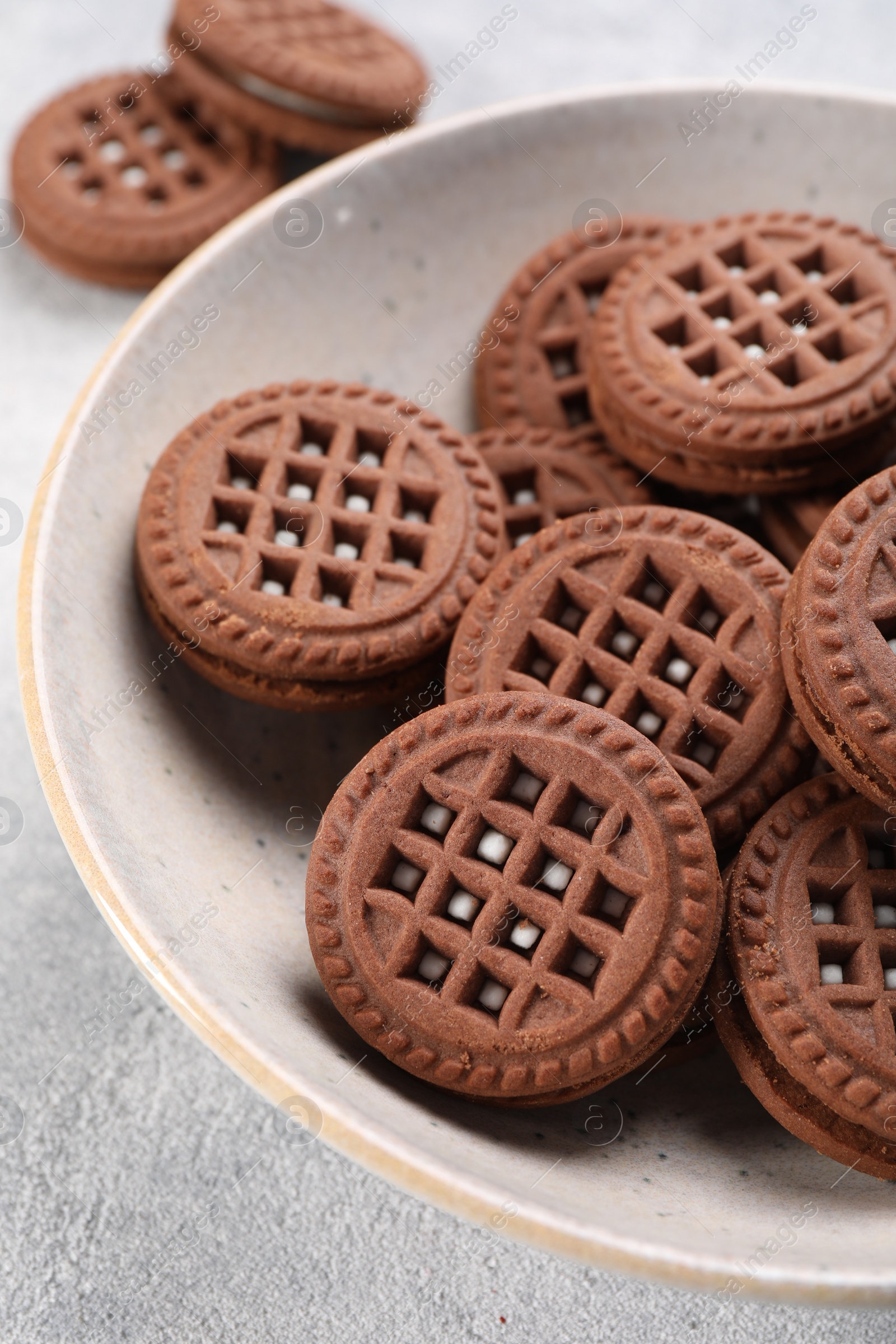 Photo of Tasty chocolate sandwich cookies with cream on light grey table, closeup