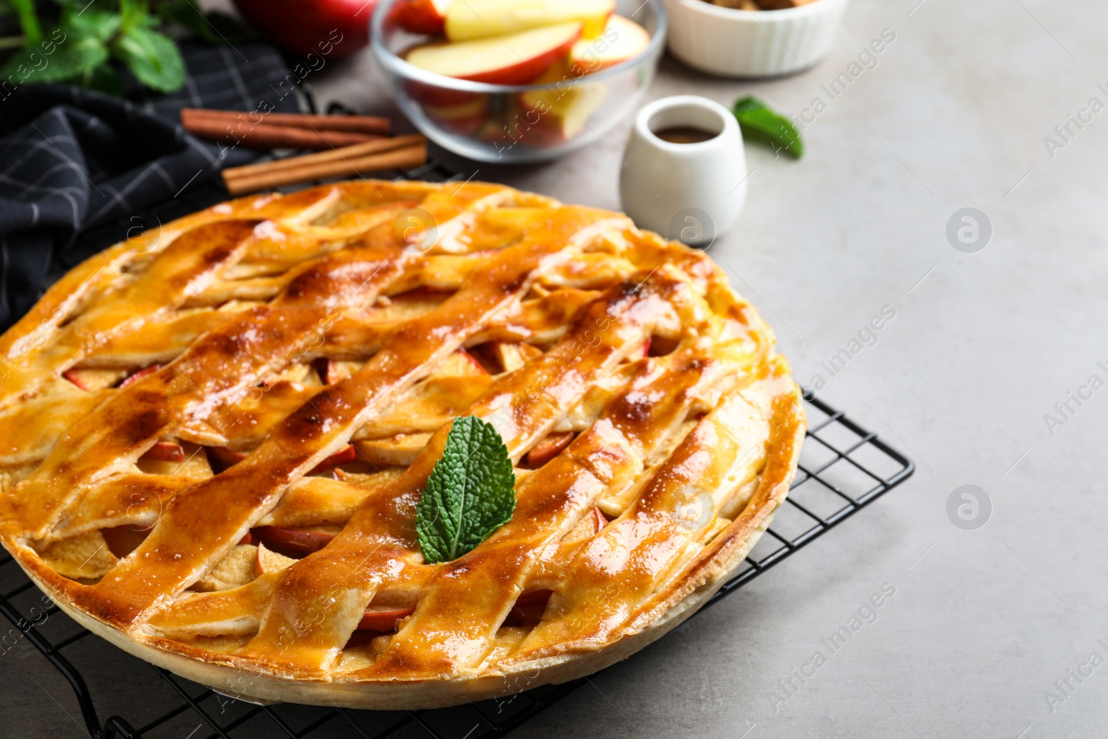 Photo of Fresh traditional apple pie with mint on light grey table