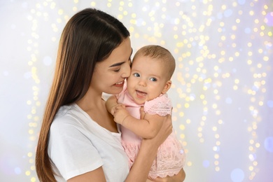 Photo of Portrait of happy mother with her baby against blurred lights. Space for text