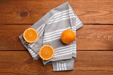 Striped kitchen towel and oranges on wooden table, flat lay