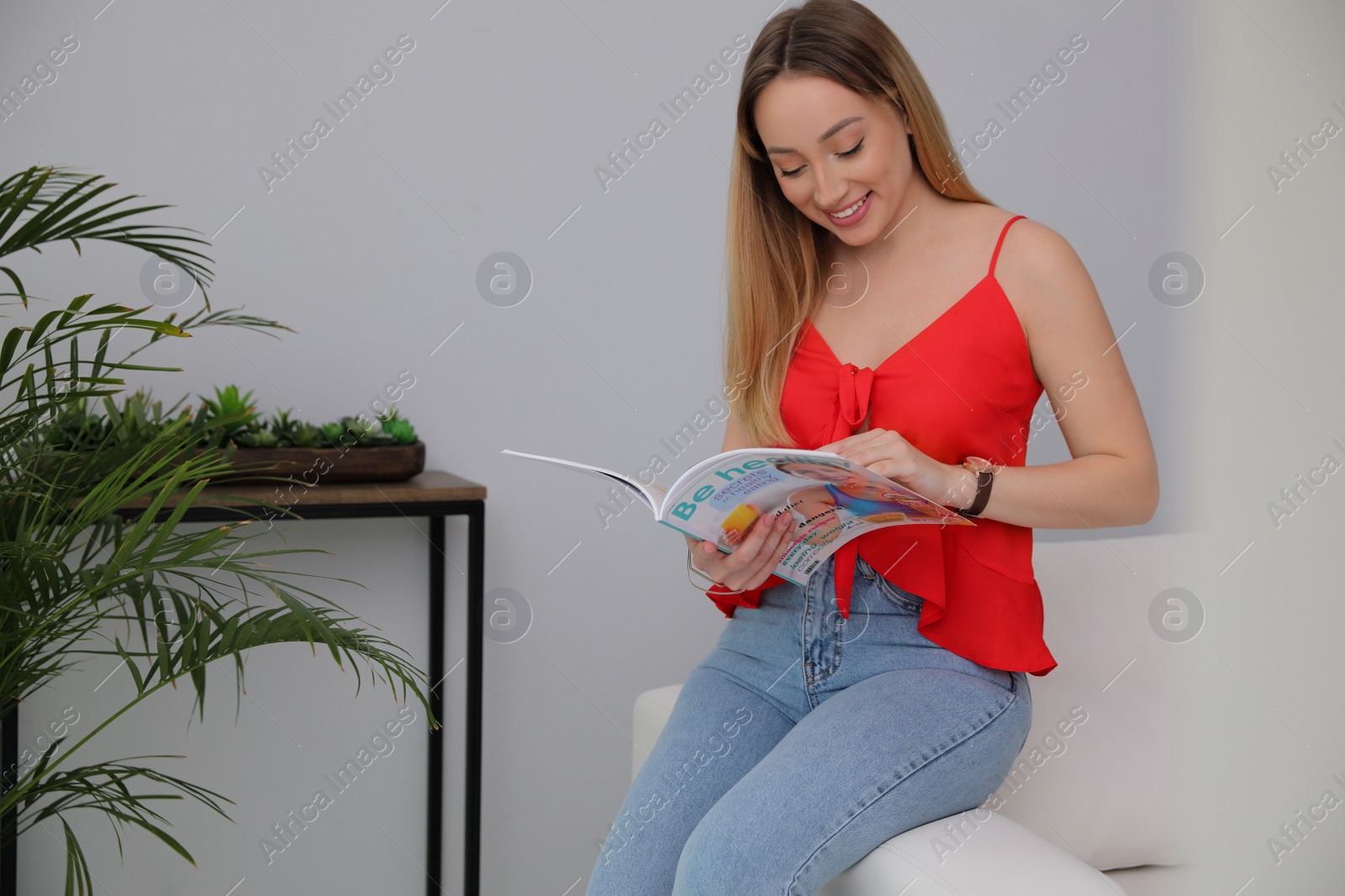 Photo of Happy woman reading magazine in living room