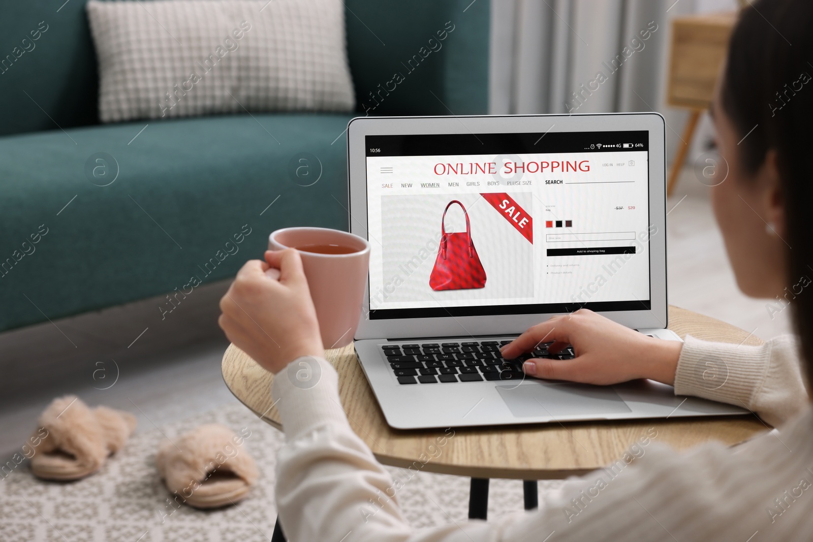 Photo of Woman with cup of tea shopping online during sale on laptop at home, closeup