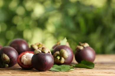 Photo of Delicious tropical mangosteen fruits on wooden table. Space for text