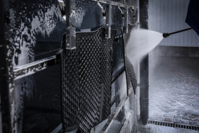 Cleaning automobile floor mats with high pressure water jet at car wash