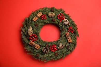 Photo of Beautiful Christmas wreath on red background, top view