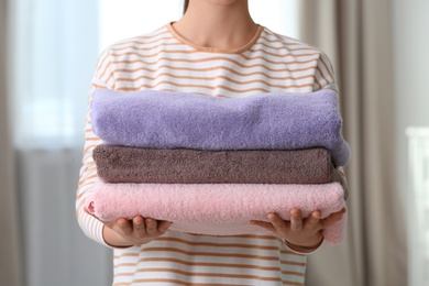 Photo of Young woman holding clean laundry at home, closeup