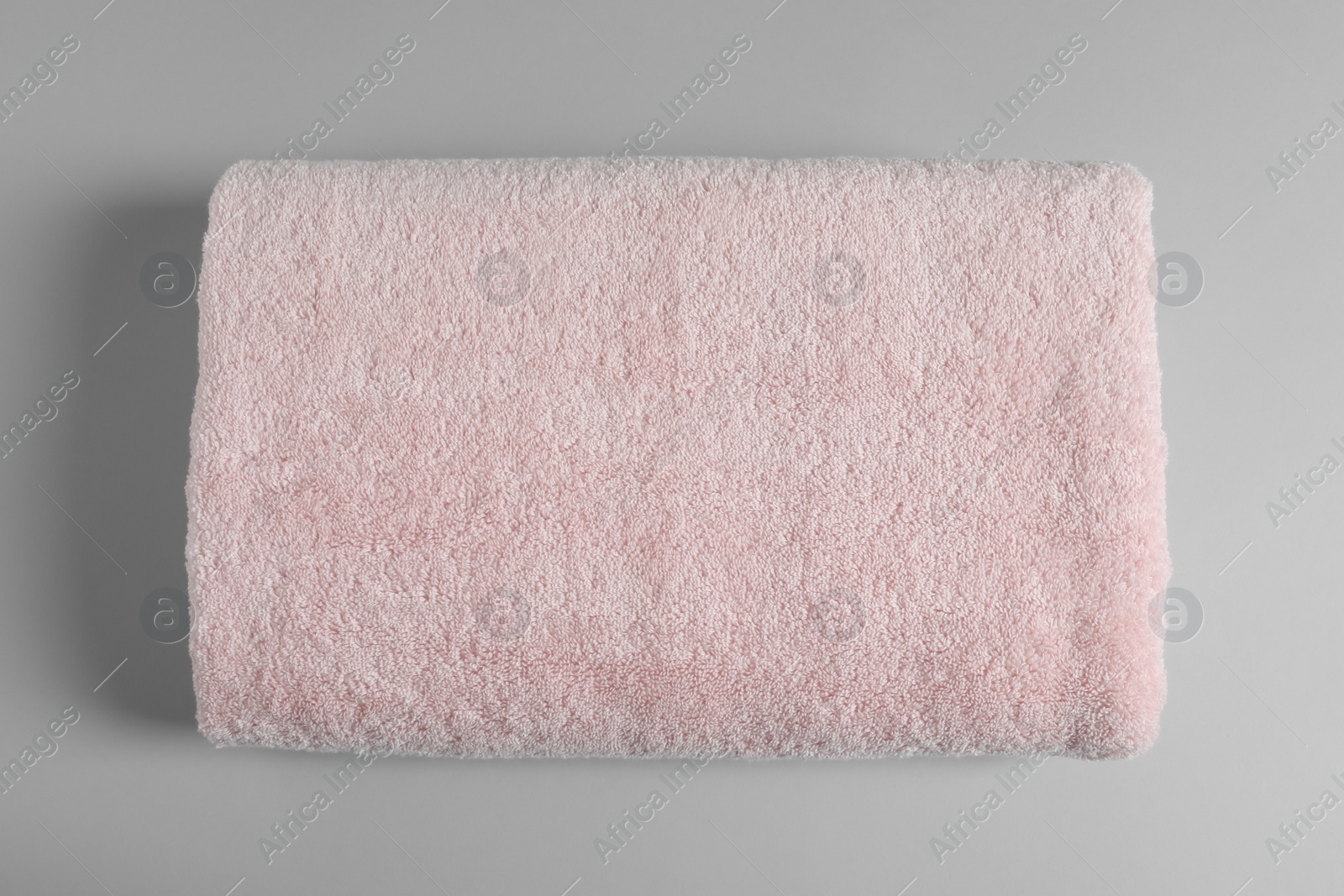 Photo of Soft folded towel on light background, top view