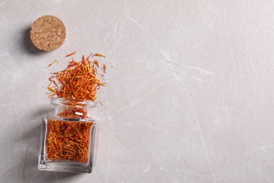 Photo of Aromatic saffron and glass jar on light gray table, flat lay. Space for text