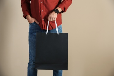 Young man holding paper bag on color background, closeup.  Mockup for design