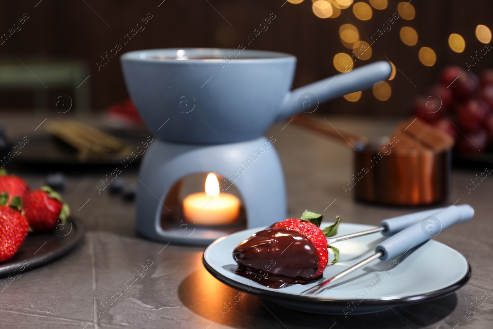 Photo of Plate with strawberry dipped into chocolate fondue on table. Space for text