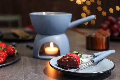 Photo of Plate with strawberry dipped into chocolate fondue on table. Space for text