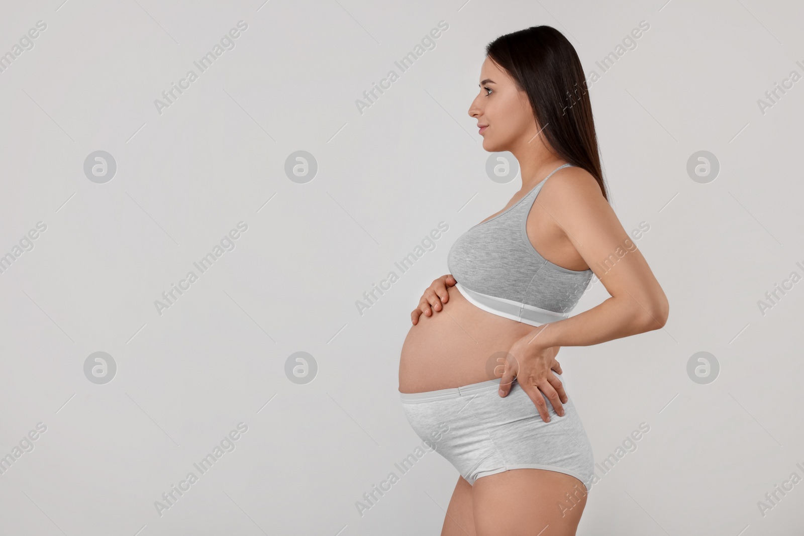 Photo of Beautiful pregnant woman in comfortable maternity underwear on grey background, space for text