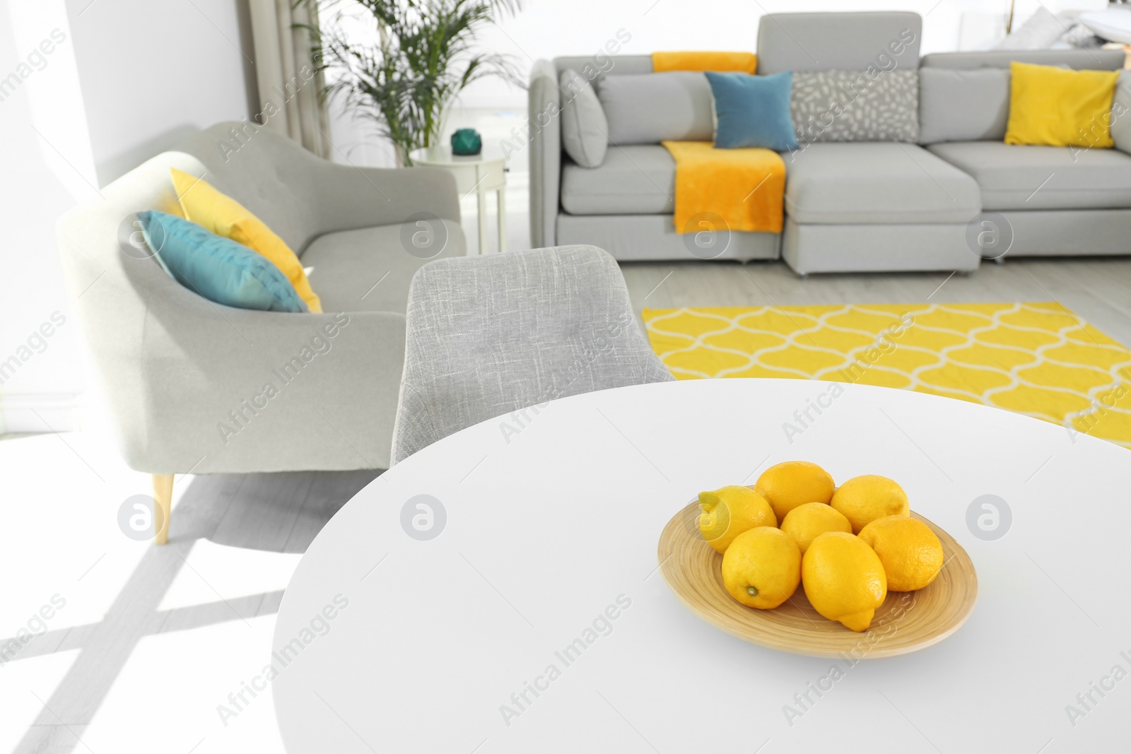 Photo of Plate with fresh lemons on table in living room. Color ideas for interior