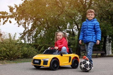 Photo of Cute little children with toy car and soccer ball having fun outdoors. Space for text