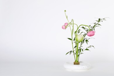 Photo of Beautiful ikebana for stylish house decor. Floral composition with fresh flowers and branches on white background, space for text
