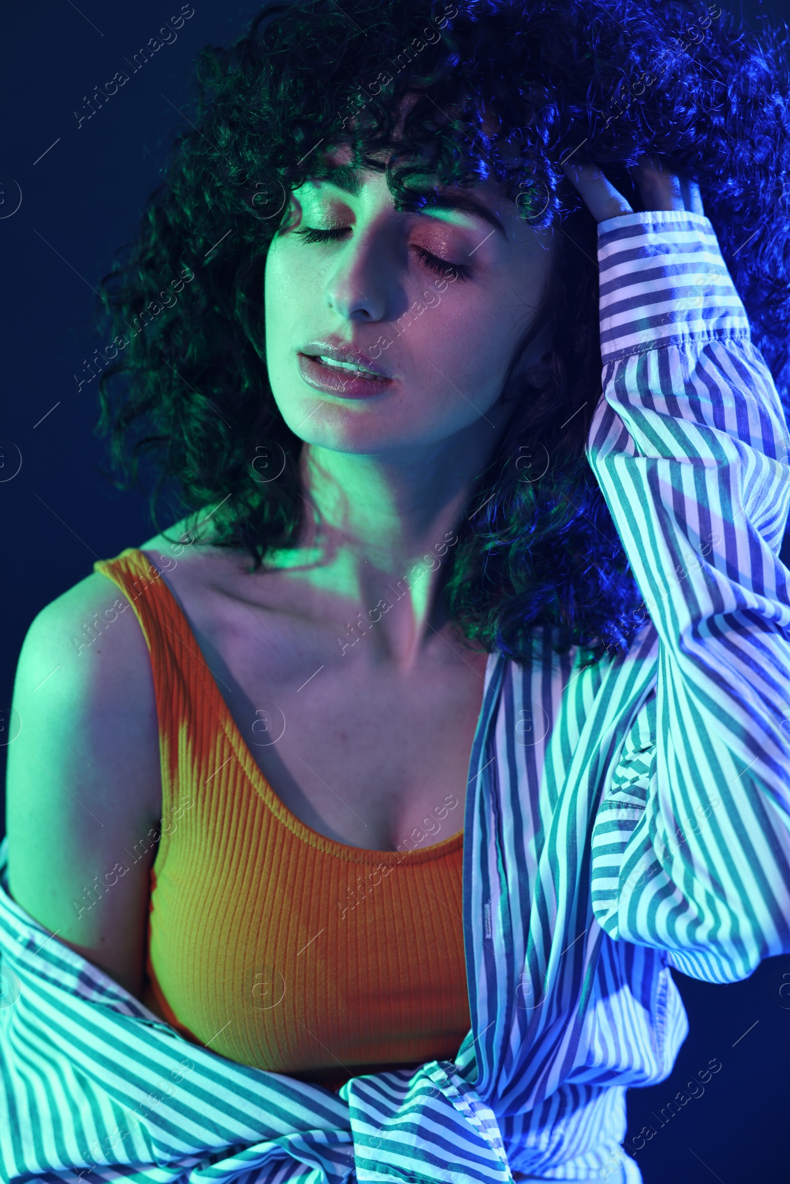 Photo of Beautiful young woman posing on color background in neon lights