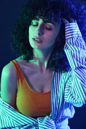 Beautiful young woman posing on color background in neon lights