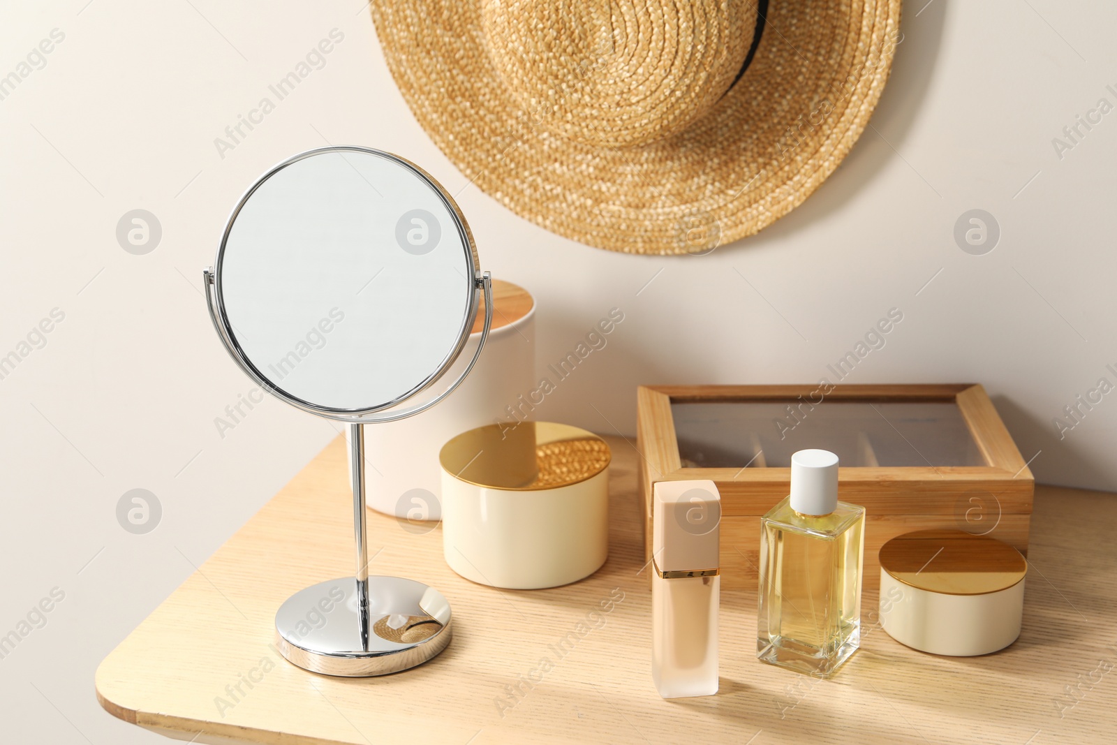 Photo of Mirror, perfume and makeup products on dressing table in room