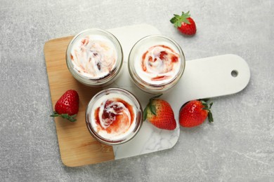 Photo of Tasty yoghurt with jam and strawberries on grey table, top view