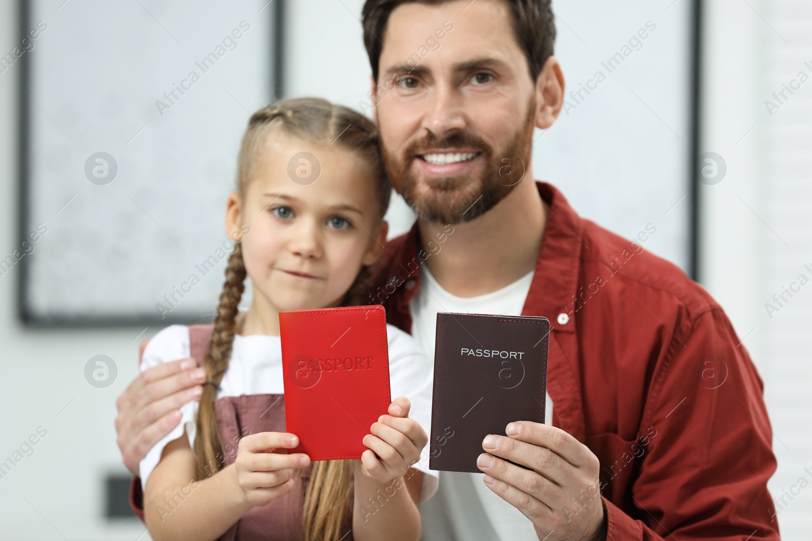 Photo of Immigration. Happy man and his daughter with passports indoors, selective focus