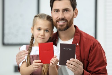 Photo of Immigration. Happy man and his daughter with passports indoors, selective focus