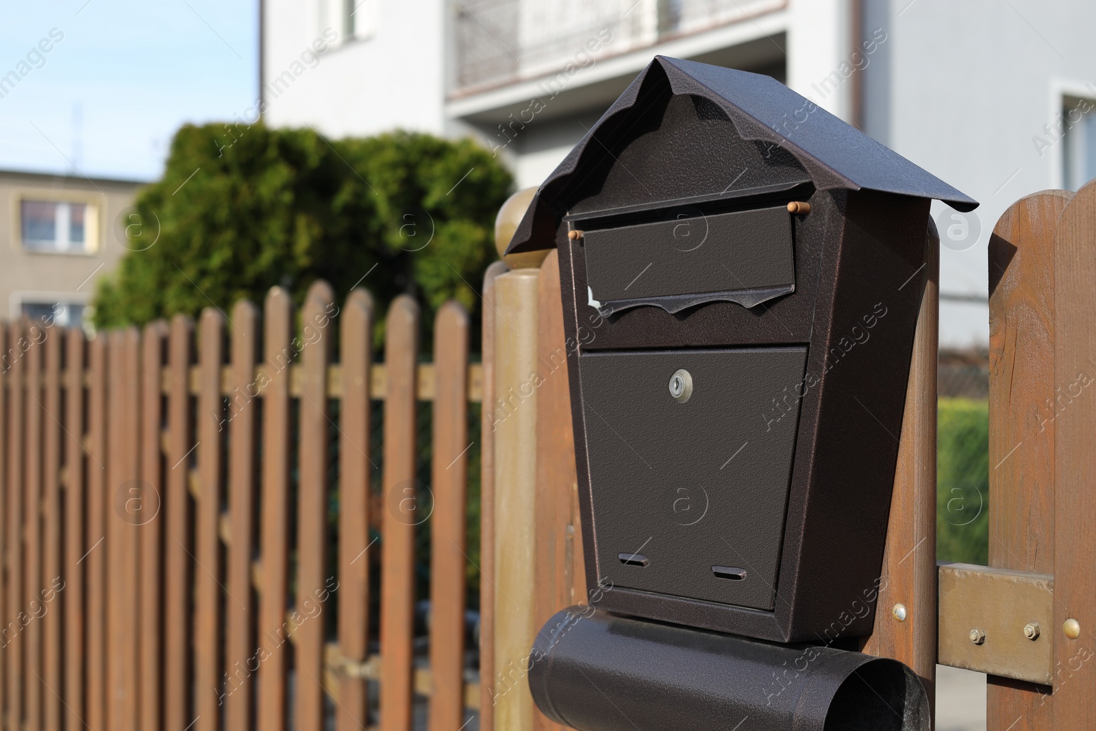 Photo of Beautiful house shaped mailbox with newspaper holder on wooden fence outdoors, space for text