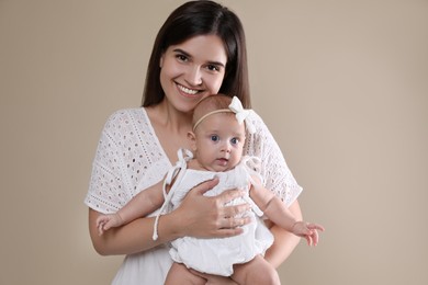 Beautiful mother with her cute baby on beige background